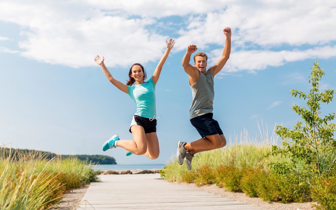 przeciwdziałanie kontuzjom biegaczy, kobieta i mężczyzna podskakują nad brzegiem morza
