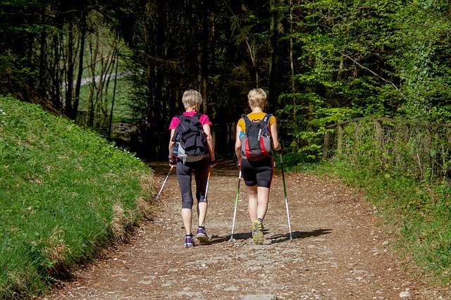 dwie panie uprawiają Nordic Walking po lesie, stosując wkładki do butów trekkingowych